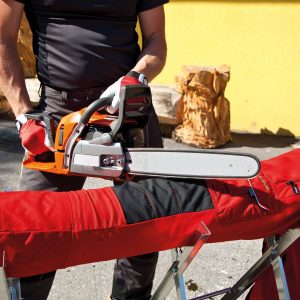 Un homme approche une tronçonneuse d\'une mannequin qui porte un pantalon anti-coupures.