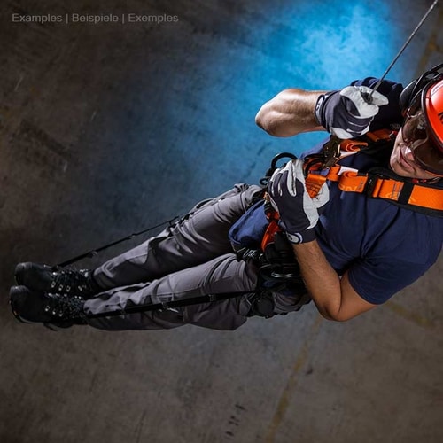 sangles de secours, personne portant un casque de sécurité et des gants portant une ceinture de sécurité orange lors d’une descente en rappel dans un environnement sombre
