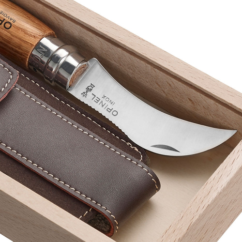 Gros plan du couteau incurvé avec la gravure « OPINEL INOX » et de l’étui en cuir dans la boîte en bois clair