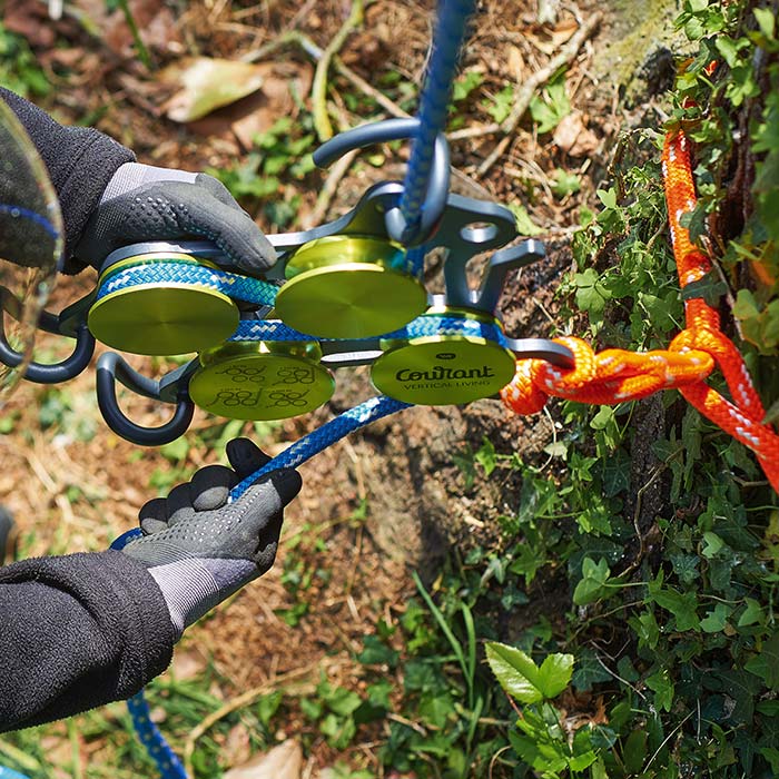Le produit Hulk avec des éléments ronds verts et un cadre en métal noir, relié par des cordes bleues et oranges, est tenu par une personne portant des gants