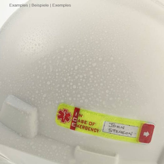 Vital ID d’urgence jaune avec flèche rouge et texte « EN CAS D’URGENCE » avec le nom manuscrit « John Stenson » sur un casque blanc avec des gouttelettes d’eau, fabricant Vital ID