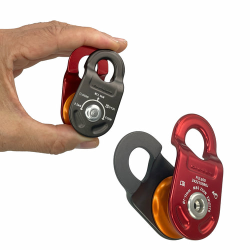 La main tient une roue avec un boîtier rouge et noir et un rouleau orange, à côté se trouve une autre poulie du même type, le nom du fabricant n’est pas visible