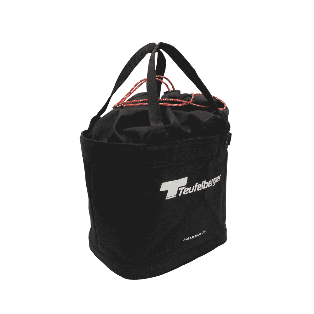 Bucket Mule de Teufelberger, sac rond noir avec deux poignées noires et fermeture à cordon rouge, devant avec logo Teufelberger blanc et inscription « AMBASSADOR LINE »