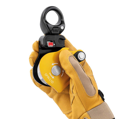 Poulie Petzl Spin L1D avec gant sur une main tenant la poulie