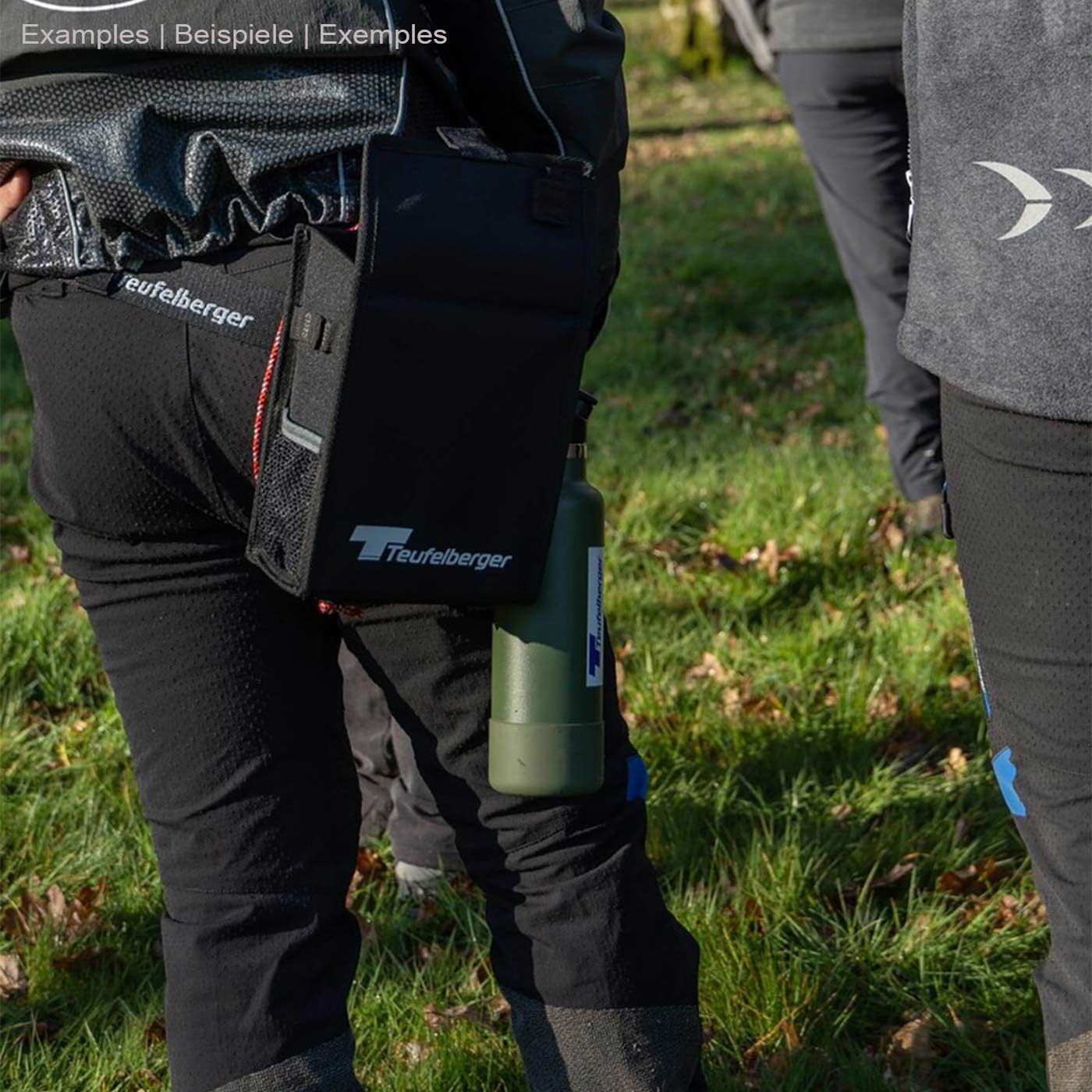 Mini Mule de Teufelberger, attaché à la hanche d’une personne, sac noir avec le logo Teufelberger, à côté une bouteille verte avec le logo Teufelberger