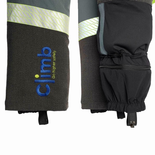 Détail de la partie inférieure des jambes du pantalon de protection contre les coupures Climb avec bande réfléchissante, logo « climb » brodé en bleu et jaune et poignets élastiques avec fermeture à crochet