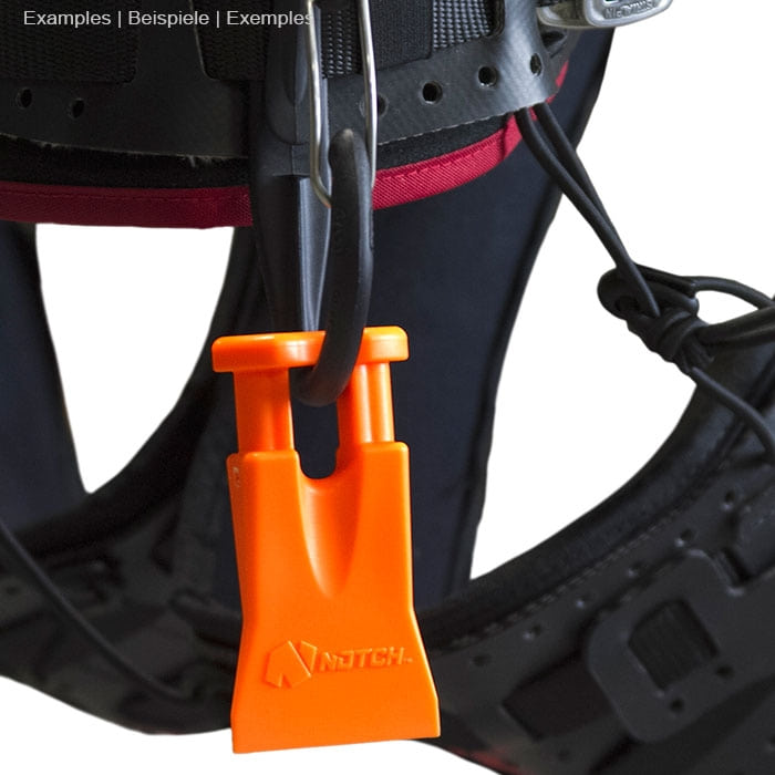 Climbers Best Friend Wedge de Notch, un coin en plastique orange avec deux tiges courtes s’accroche à un harnais d’escalade noir avec des accents rouges