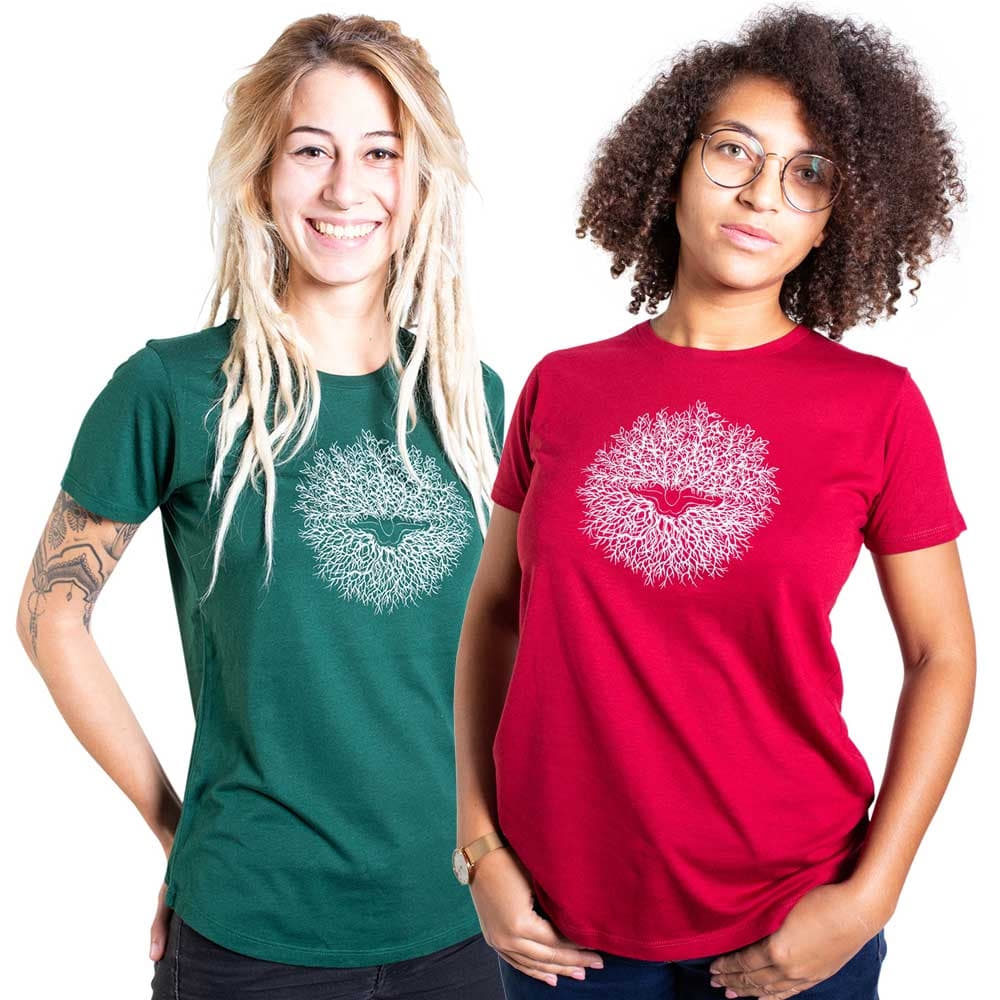 Deux femmes portent des T-shirts avec le motif « Ascension », l’un en vert et l’autre en rouge, les deux T-shirts montrent un motif circulaire blanc avec un oiseau au milieu.