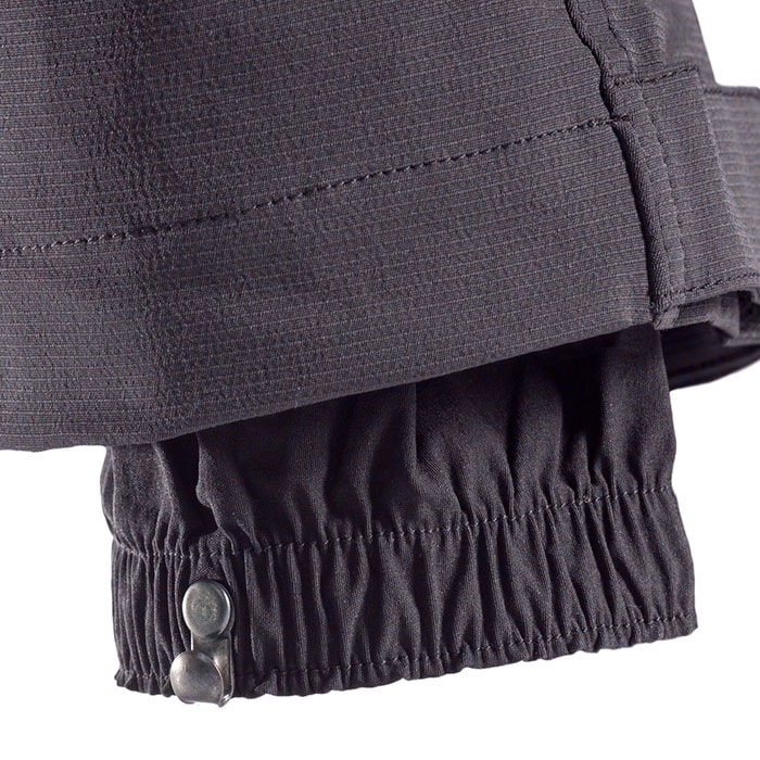 Pantalon d’escalade SIP, gros plan de l’ourlet de la jambe du pantalon avec ceinture élastique et deux boutons métalliques pour la fermeture