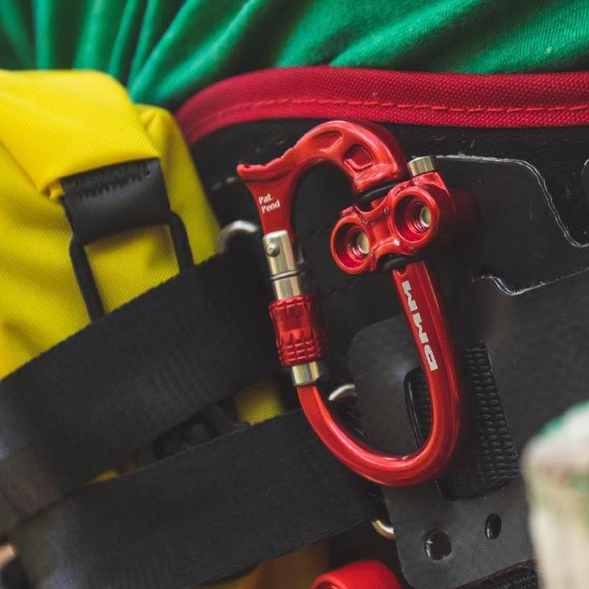 Micro Vault de DMM, mousqueton rouge avec fermeture à vis attaché à une sangle de sac à dos noire