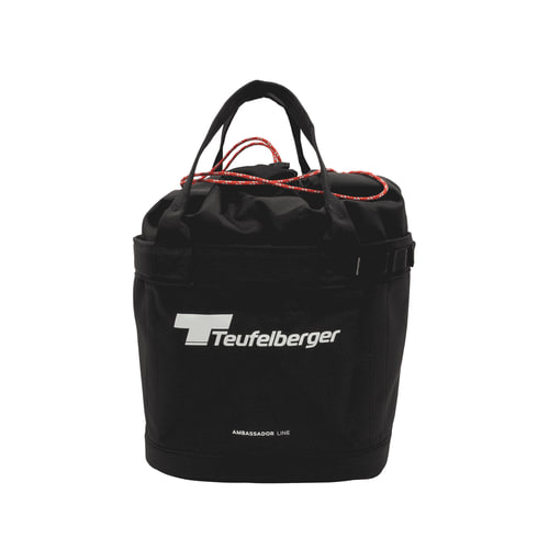 Bucket Mule de Teufelberger, sac rond noir avec deux poignées noires et fermeture à cordon rouge, devant avec logo Teufelberger blanc et inscription « AMBASSADOR LINE »