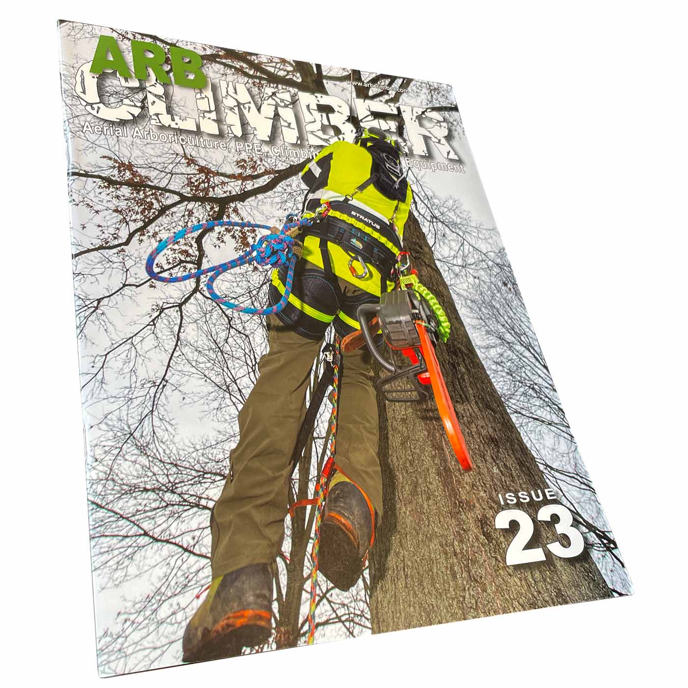 Magazine Arb Climber n° 23 avec un grimpeur en tenue de protection jaune sur un tronc d’arbre, tronçonneuse sur le côté, titre en grosses lettres en haut et numéro 23 en bas à droite, photographié légèrement en biais