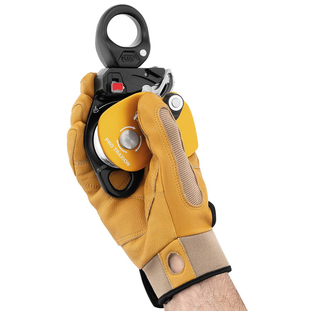 Poulie à corde Petzl Pro Traxion jaune et noir, tenue d’une main avec un gant de travail jaune