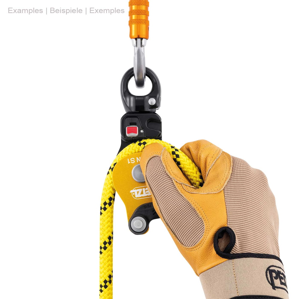 Petzl Spin S1, poulie jaune et noire avec anneau métallique sur le dessus, corde jaune et main avec gant de travail tenant la corde