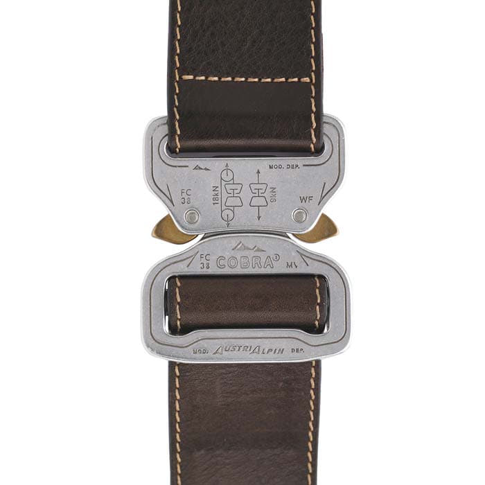 Gros plan sur le fermoir en métal de la ceinture en cuir Cobra 38 d’AustriAlpin avec bracelet en cuir marron et inscriptions