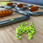 Hardware NFC Tag de Scannable, de nombreux petits tags NFC jaune-vert reposent sur une table en bois devant plusieurs mousquetons à fermeture orange
