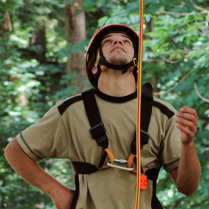 Un homme porte un casque rouge et un harnais d’escalade auquel est attachée une corde tressée rouge et jaune, nom du produit XP-e