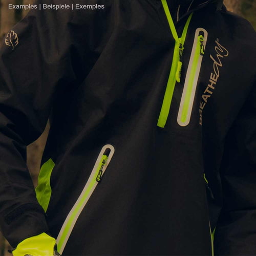 Gros plan d’une personne portant une veste smockée noire BreatheDry avec des détails verts et des poches zippées