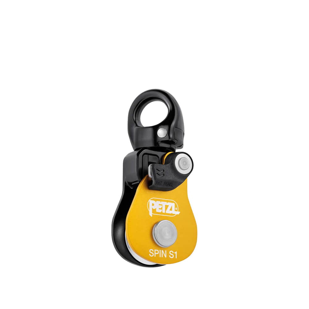 Petzl Spin S1, poulie jaune et noire avec anneau métallique sur le dessus et bouton blanc sur plaque jaune