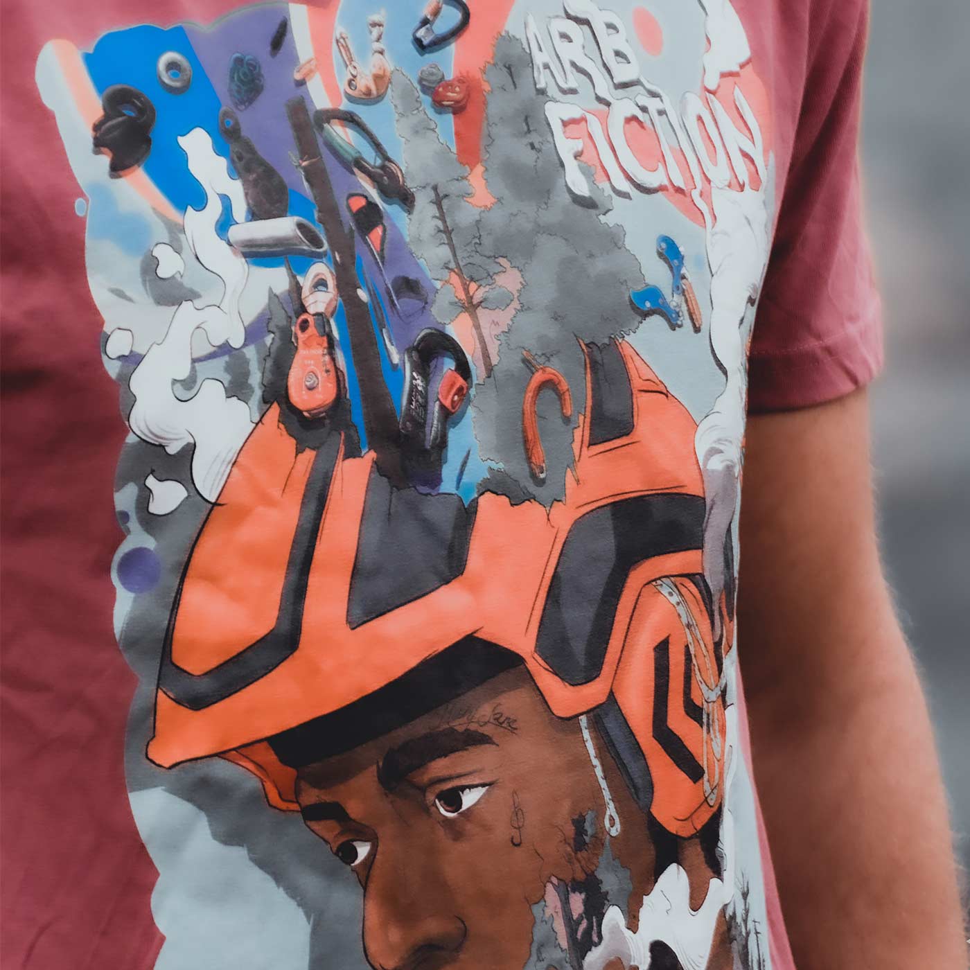 Gros plan d’un T-shirt rouge avec le même imprimé coloré d’un homme avec un casque orange et le texte « ARB FICTION », nom du produit Mind Fuck