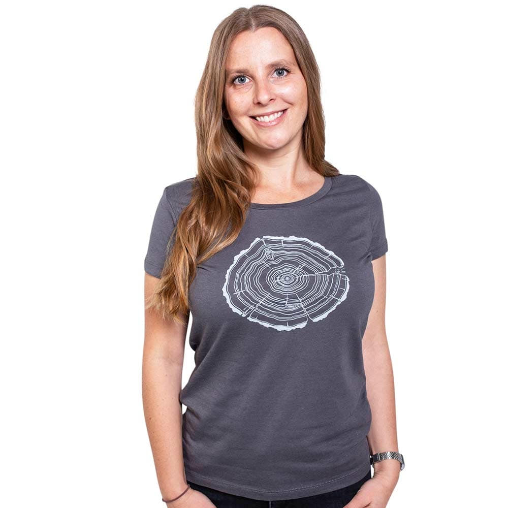 Une femme aux longs cheveux blonds porte un t-shirt gris Treeslice Women avec un motif de tronc d’arbre blanc sur le devant
