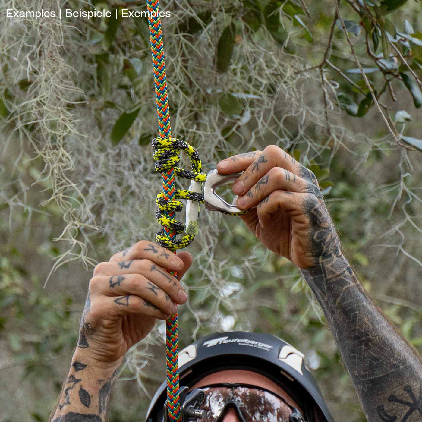 prusikLOOP fimble, une corde d’escalade avec une partie en métal argenté, tenue par les mains tatouées d’une personne avec un casque, dans un environnement forestier