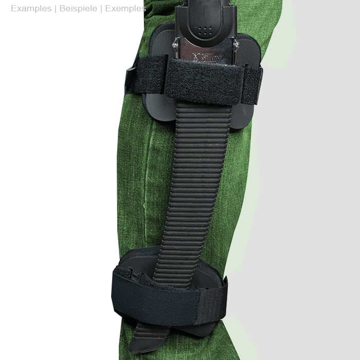 La personne porte un pantalon vert, le Talon Mount est attaché à la jambe avec une scie à main noire