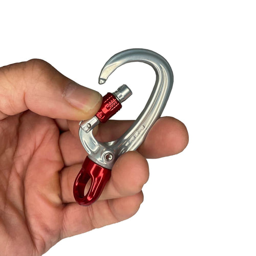 Mousqueton XSRE Swivel Lock en argent avec verrou tournant rouge et émerillon rouge, tenu d’une main