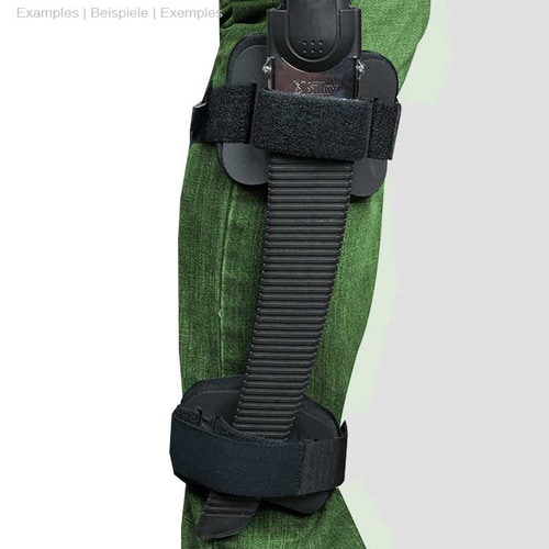 La personne porte un pantalon vert, le Talon Mount est attaché à la jambe avec une scie à main noire