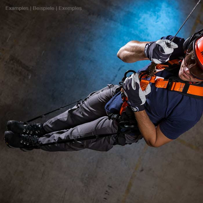 sangles de secours, personne portant un casque de sécurité et des gants portant une ceinture de sécurité orange lors d’une descente en rappel dans un environnement sombre