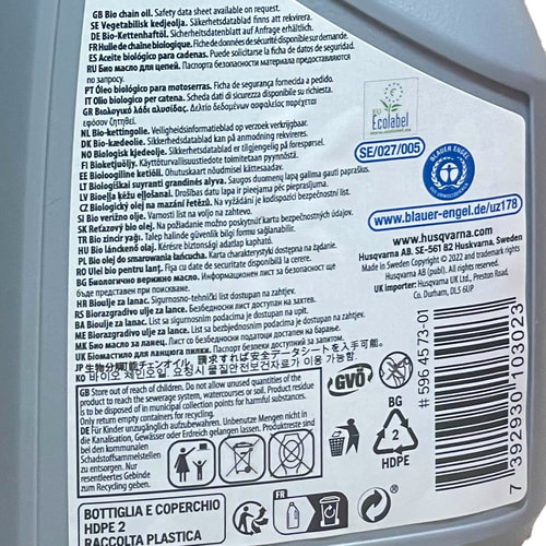 Dos de la bouteille en plastique grise avec texte en plusieurs langues, consignes de sécurité, symboles de recyclage et code-barres, coordonnées du fabricant Husqvarna visible
