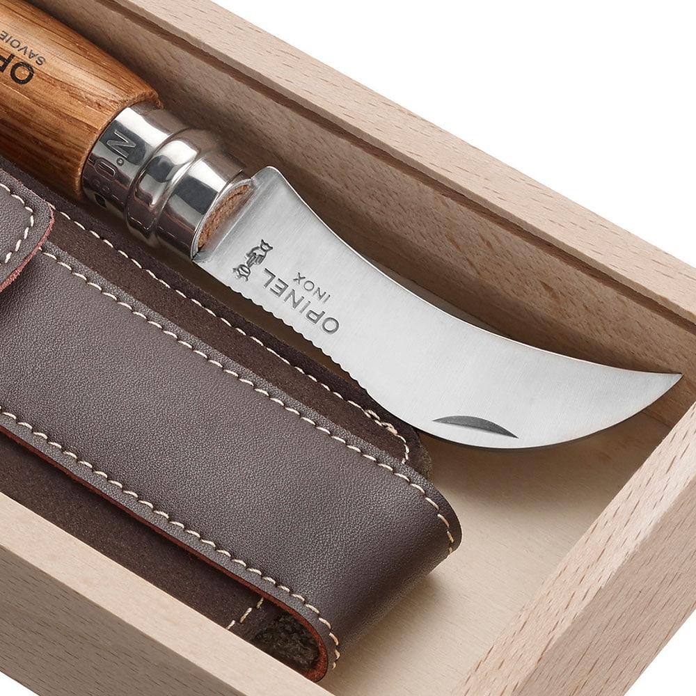 Gros plan du couteau incurvé avec la gravure « OPINEL INOX » et de l’étui en cuir dans la boîte en bois clair
