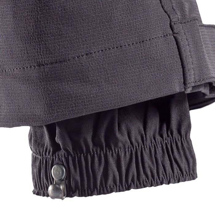 Pantalon d’escalade SIP, gros plan de l’ourlet de la jambe du pantalon avec ceinture élastique et deux boutons métalliques pour la fermeture