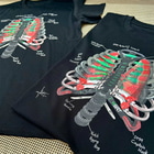 Deux t-shirts noirs Arb Ribs avec le motif de la cage thoracique imprimé sur eux à partir d’un équipement d’escalade sont posés l’un à côté de l’autre sur une surface