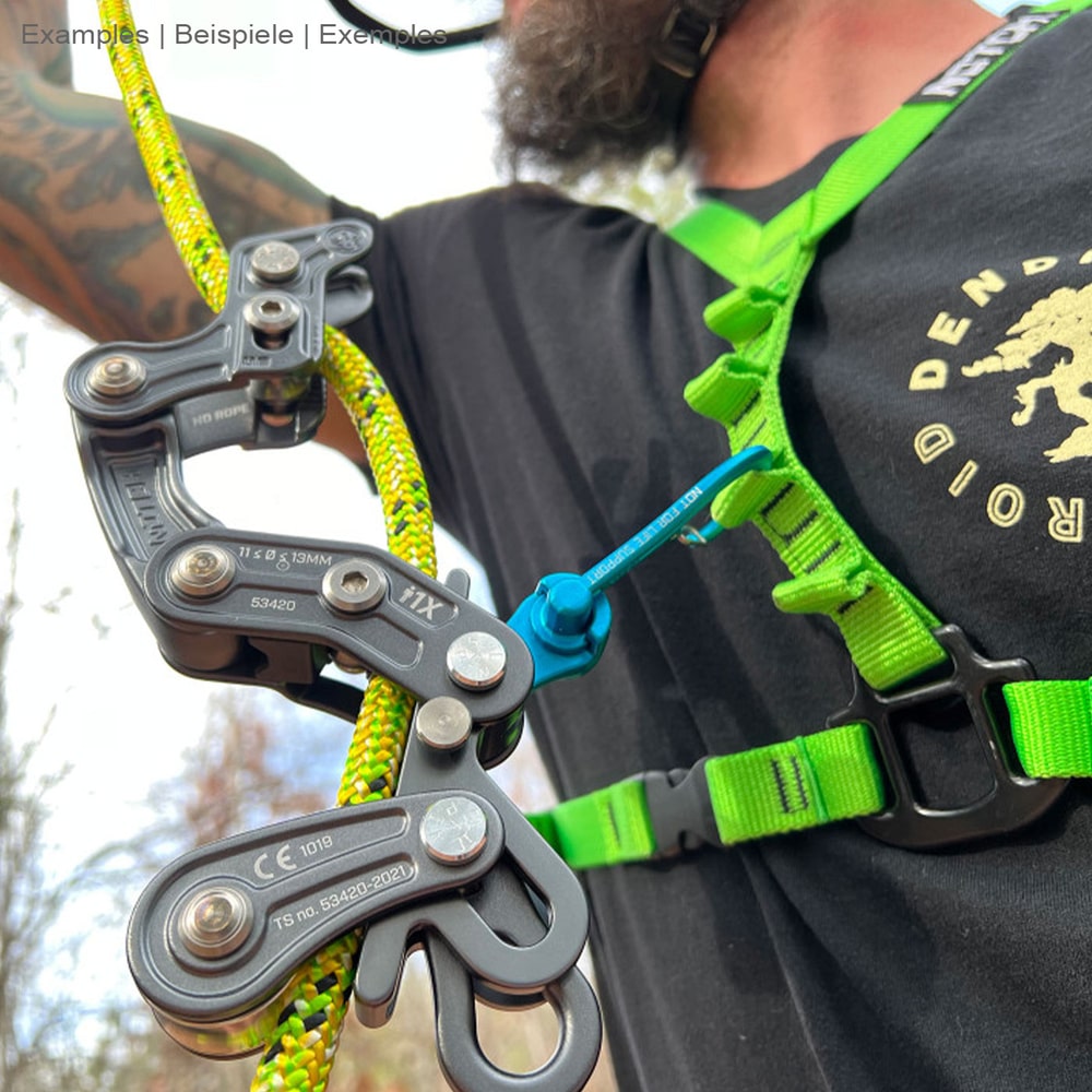 Personne portant un harnais vert et un t-shirt noir avec un mousqueton Magneato bleu attaché à celui-ci relié à un outil d’escalade noir et une corde jaune