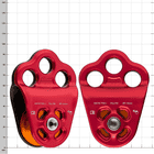 Deux poulies Hitch Climber 2 avec carter rouge et poulie orange, l’une montrant l’avant, l’autre l’arrière, sur un fond blanc avec des lignes de grille
