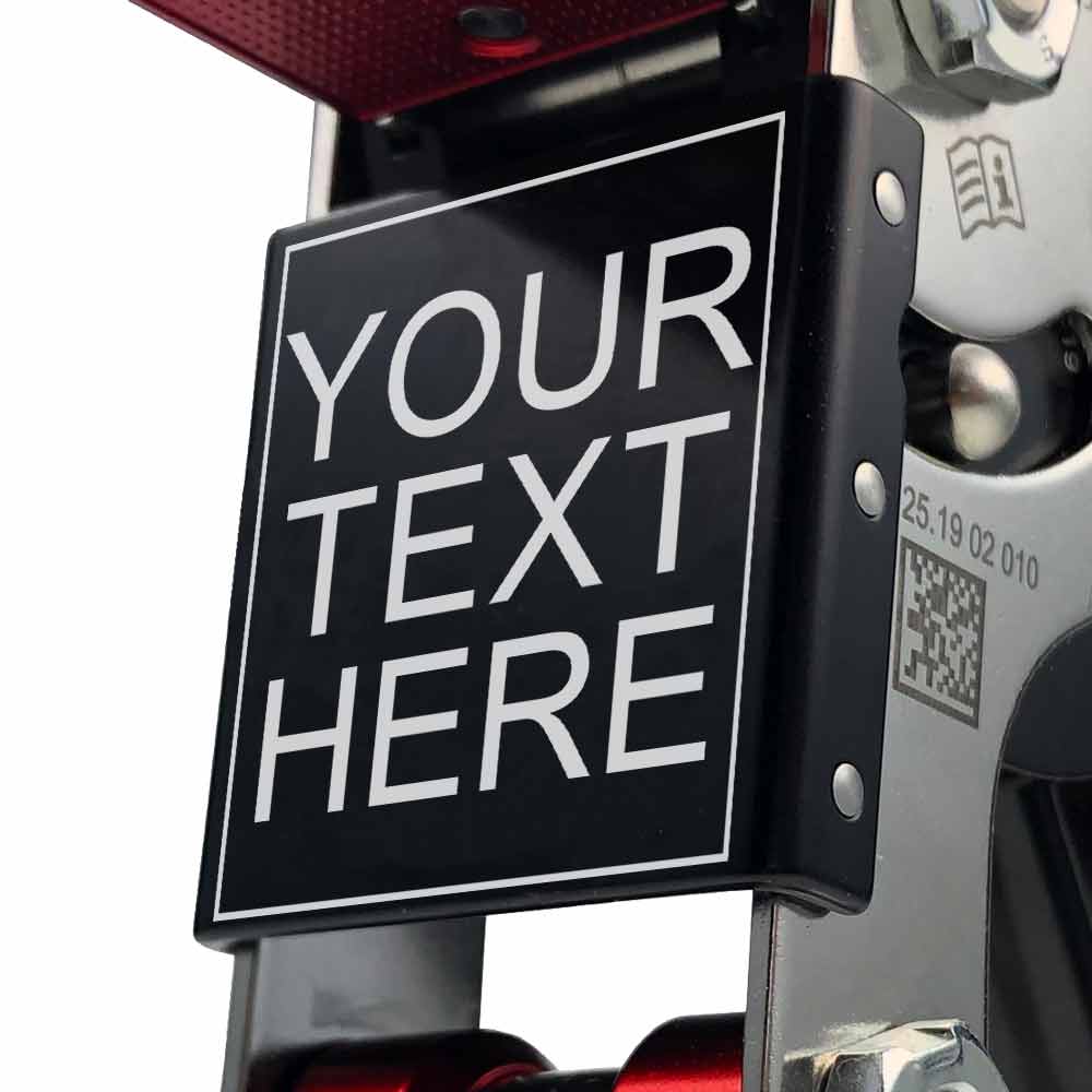 Gros plan du panneau de texte avec l’inscription « YOUR TEXT HERE » sur le SpiderJack 3 – cadre d’escalade à texte laser, vis visibles et code QR sur le cadre argenté