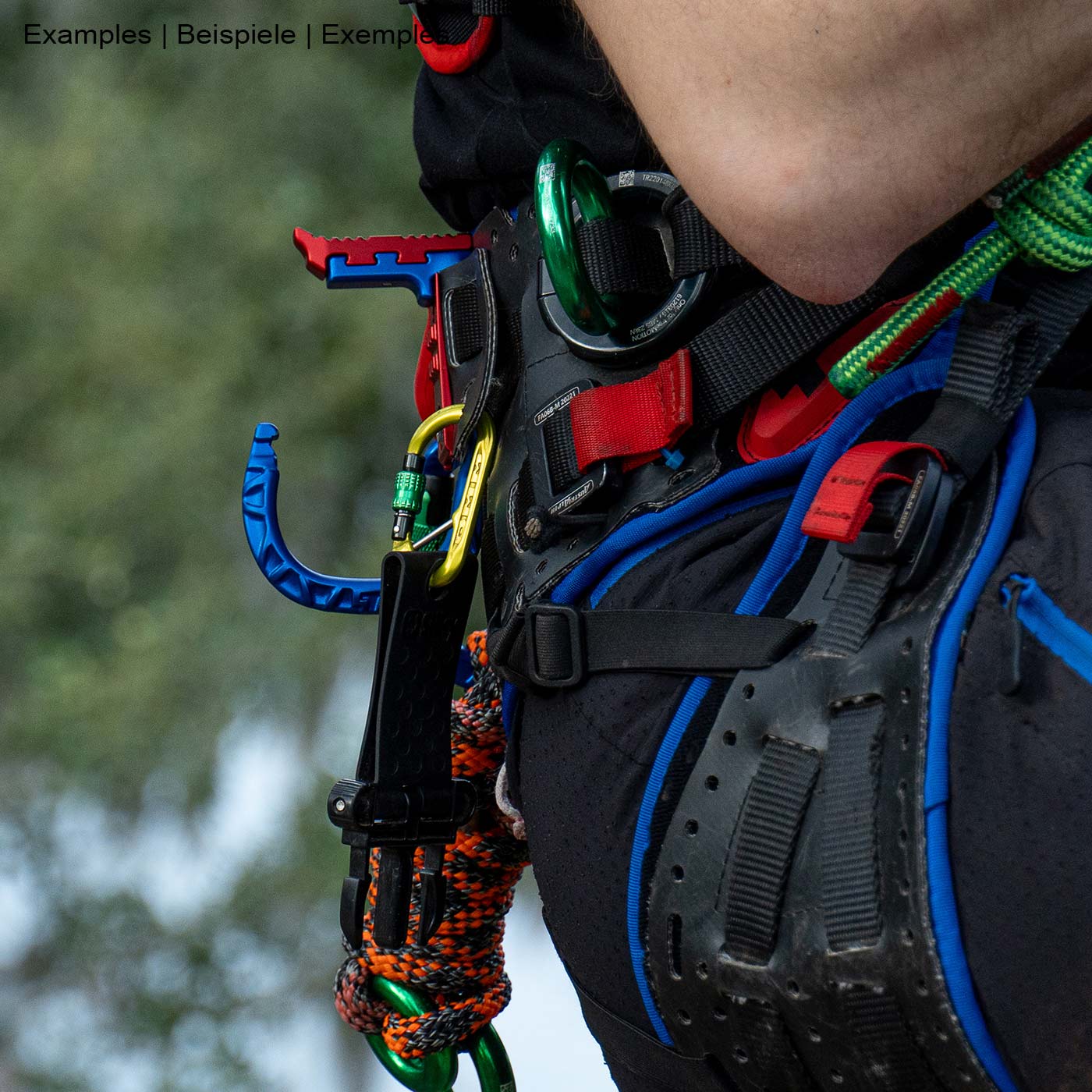 skyHOOK Open Gate en bleu et rouge attaché à un harnais d’escalade, utilisé par une personne avec du matériel d’escalade