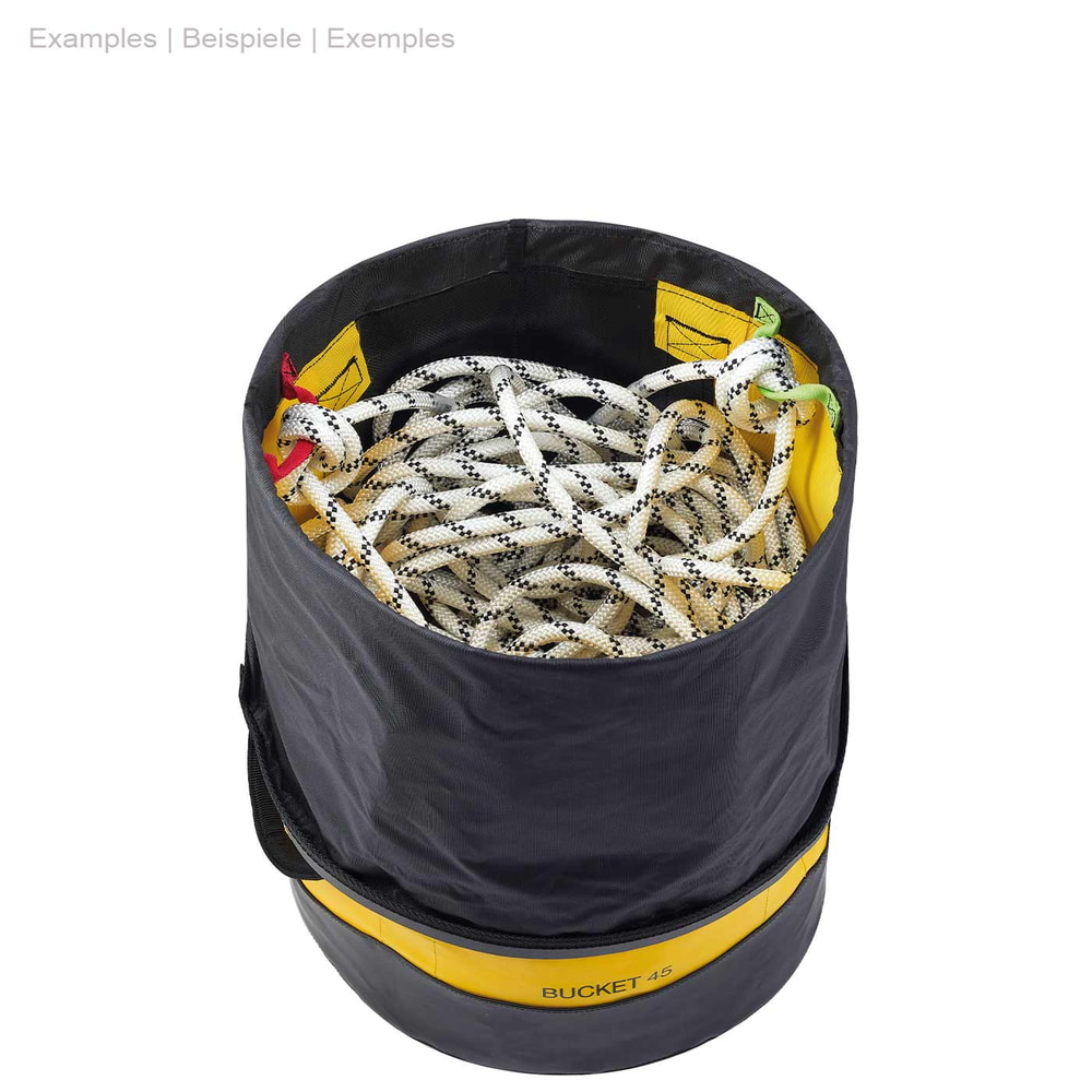 Seau rond Petzl Bucket 45 jaune et noir avec fermeture à cordon noir ouvert sur le dessus, rempli d’une corde d’escalade blanche à pois noirs