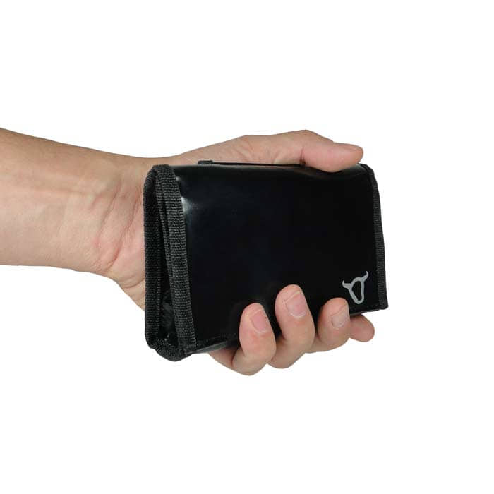 Pochette ceinture noire avec bord noir et logo tête de taureau blanc, tenue dans une main