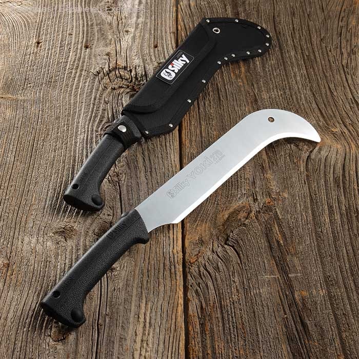 Machette Yoki 270 de Silky avec manche noir et lame argentée, posée sur fond de bois à côté d’un fourreau noir avec logo Silky