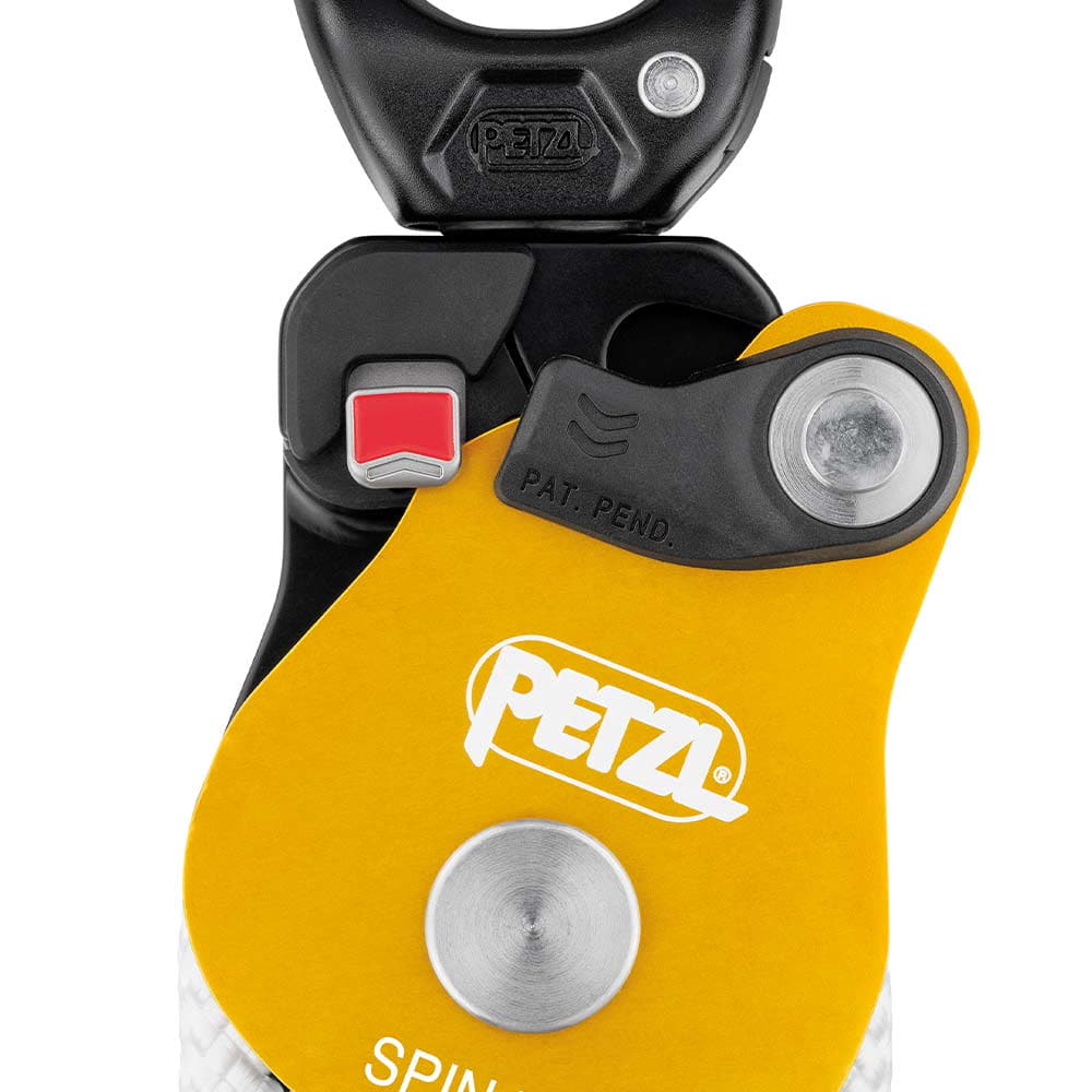 Gros plan sur le bloc Petzl Spin L2 avec boîtier jaune, logo PETZL blanc, interrupteur rouge et mousqueton noir