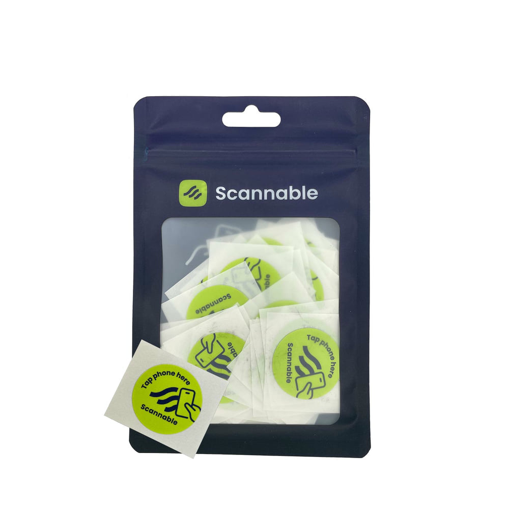 Emballage avec plusieurs autocollants de casque ronds et jaunes, des autocollants NFC avec l’inscription noire « Tap phone here Scannable » et une icône de smartphone