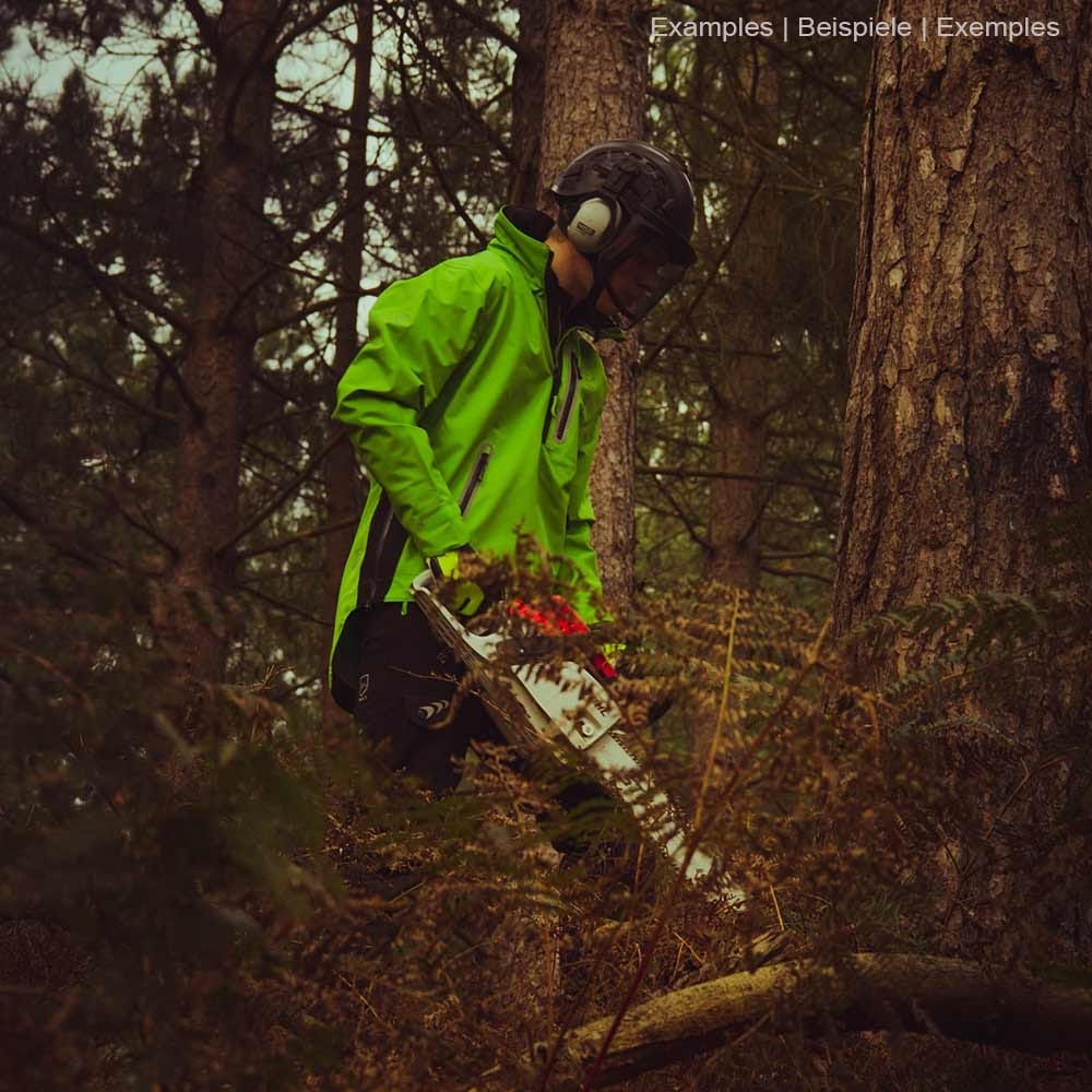 Personne portant une veste smock verte BreatheDry avec un pantalon noir et un casque dans la forêt, tenant une tronçonneuse