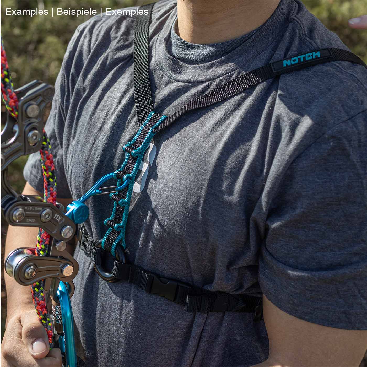 Personne portant un t-shirt gris et une sangle de poitrine Chester SRS noire avec surpiqûres turquoise, tenant un équipement d’escalade dans sa main gauche
