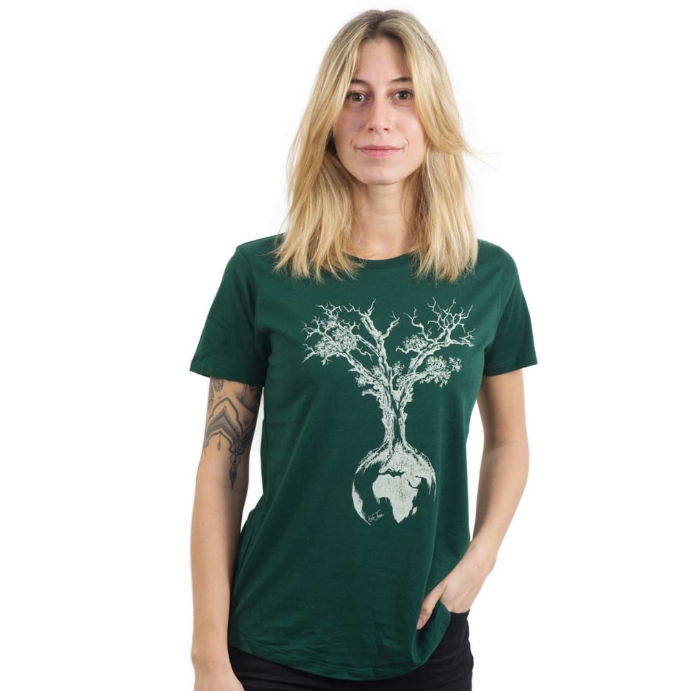 Weltenbaum T-Shirt femme en vert foncé avec arbre blanc et globe imprimé, modèle porté par une femme aux cheveux blonds et tatoué sur le bras gauche