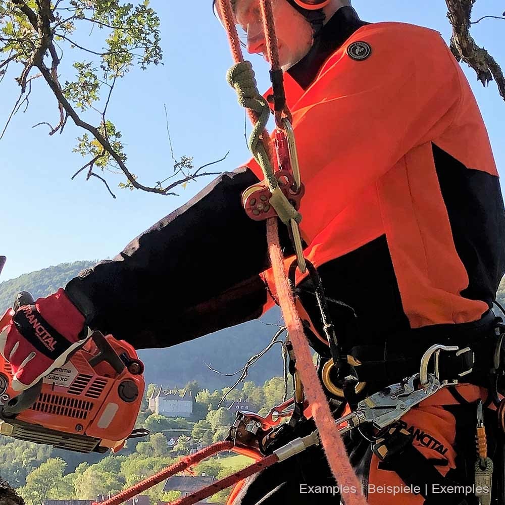 Personne portant la veste Herma de Francital en orange et noir lorsqu’elle travaille avec du matériel d’escalade et une tronçonneuse