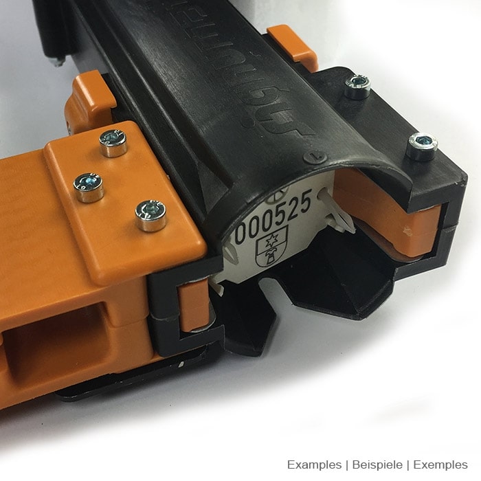 Détail de l’ouverture de l’ArboTag Magazine Lite noir avec des pièces en plastique orange et un numéro de série visible