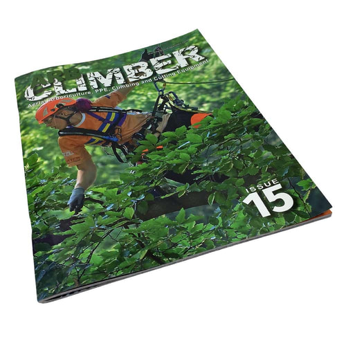 Le magazine Arb Climber n° 15 légèrement incliné, montre la même couverture avec un grimpeur d’arbres en casque orange et en haut orange, entouré de feuilles vertes