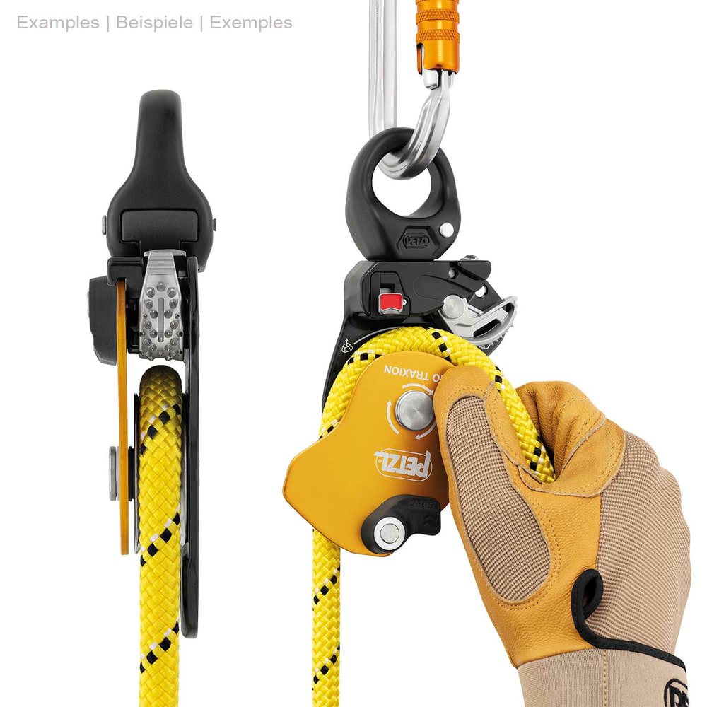 Poulie à corde Petzl Pro Traxion jaune et noire avec corde jaune, tenue d’une main avec un gant de travail, fixée sur le dessus avec un mousqueton argenté